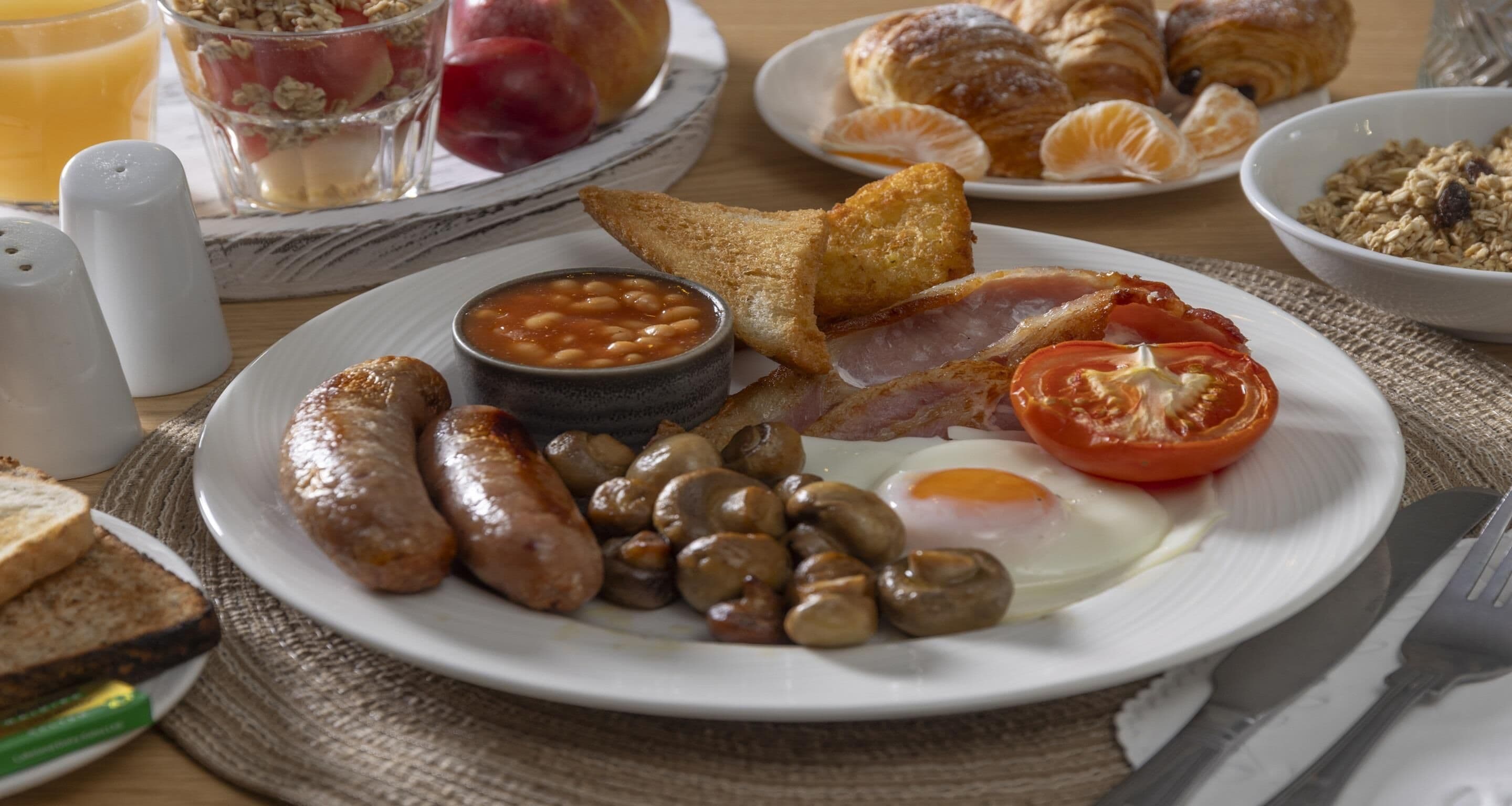 A breakfast plate with sausages, mushrooms, eggs, and tomatoes.