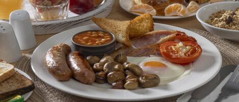 A breakfast plate with sausages, mushrooms, eggs, and tomatoes.