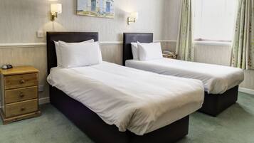 Ein Hotelzimmer mit zwei Betten, einem Holznachttisch und einem Bild an der Wand.