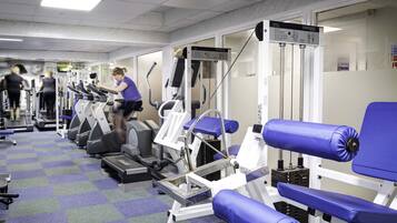 Un gimnasio con cintas de correr, elípticas y equipo de levantamiento de pesas.