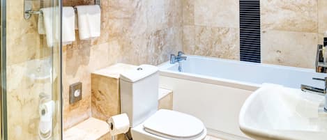 A modern bathroom with a glass shower enclosure, a toilet, a bathtub, and a sink.