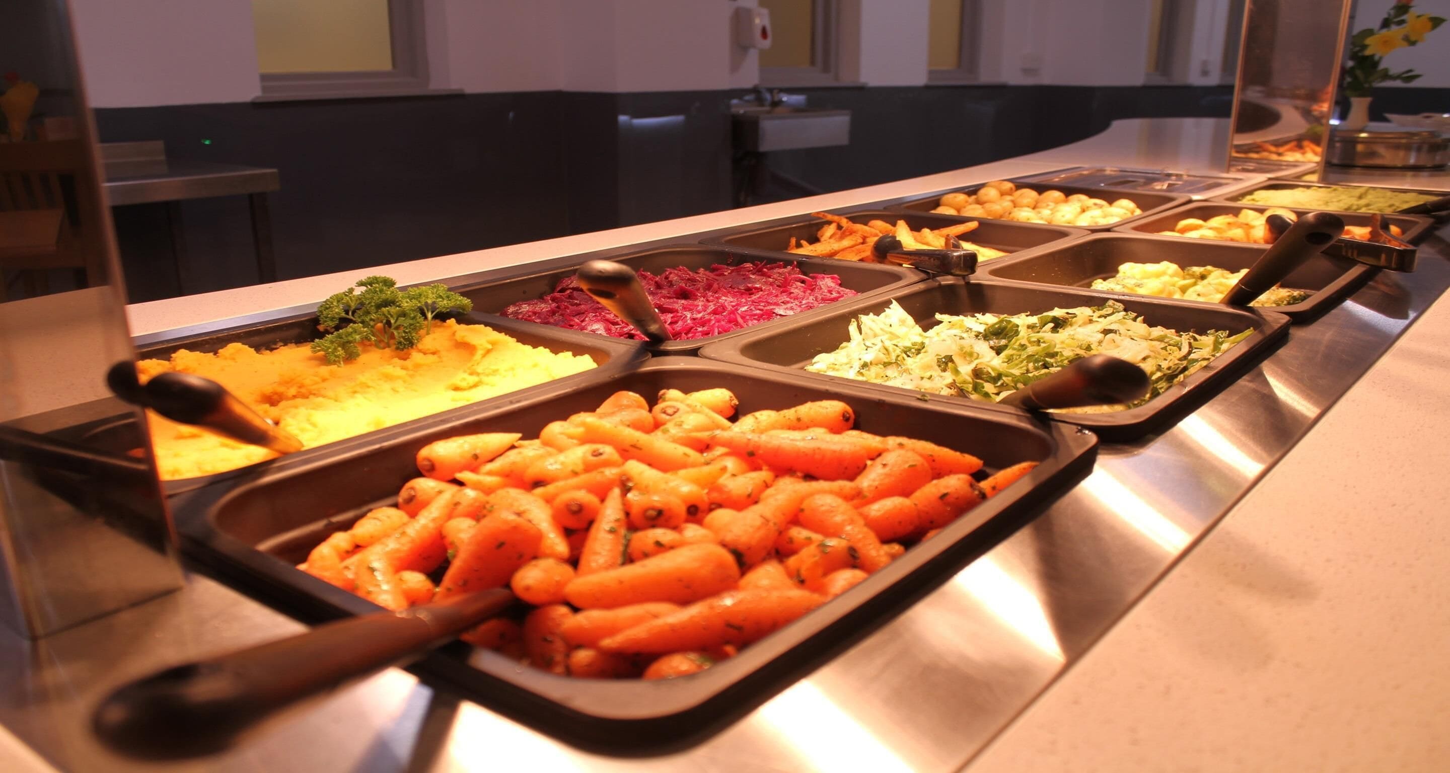 A buffet with various dishes including carrots, potatoes, and other vegetables.