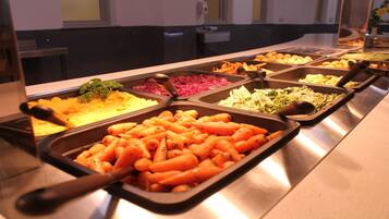 A buffet with various dishes including carrots, potatoes, and other vegetables.