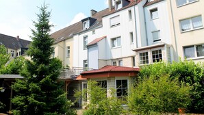A row of townhouses with a red roof, white walls, and multiple windows. - TM Apart Hotel Essen (Essen)