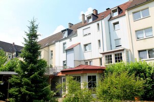 Una hilera de casas urbanas con techo rojo, paredes blancas y numerosas ventanas.