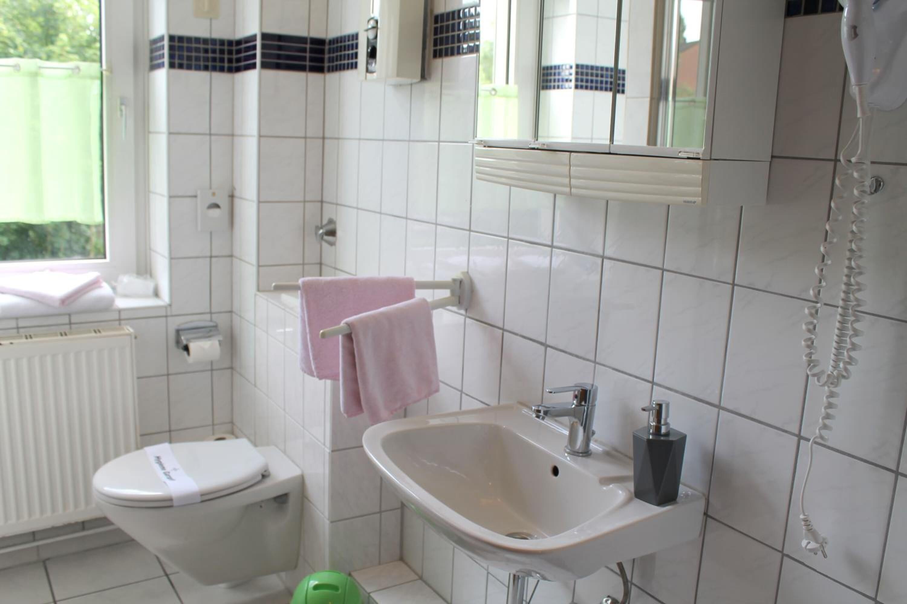 Casa de banho com sanita, lavatório e suporte para toalhas.