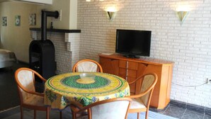 A dining area with a round table, chairs, a television, and a brick wall. - TM Apart Hotel Essen (Essen)