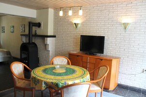 Un comedor con una mesa redonda, sillas, un televisor y una pared de ladrillo.