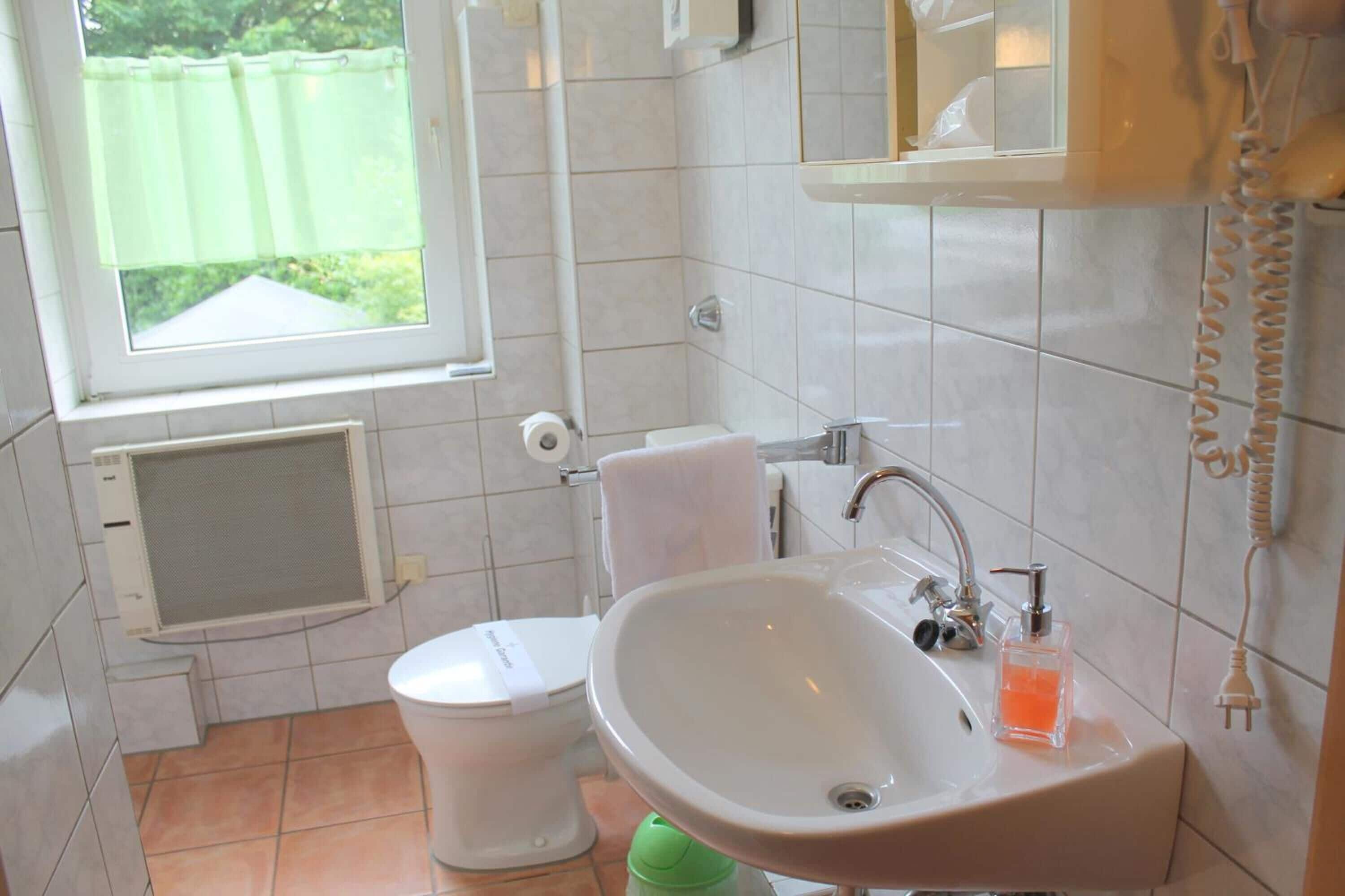 Une salle de bain avec des toilettes, un lavabo et une fenêtre.