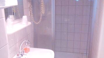 A bathroom with a sink, mirror, and shower.
