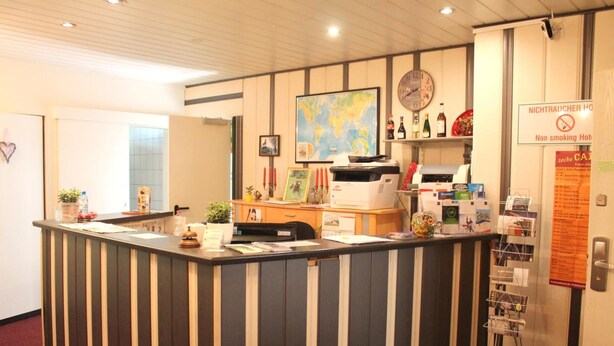 A reception desk with a world map, a clock, and a non-smoking sign. - TM Apart Hotel Essen (Essen)