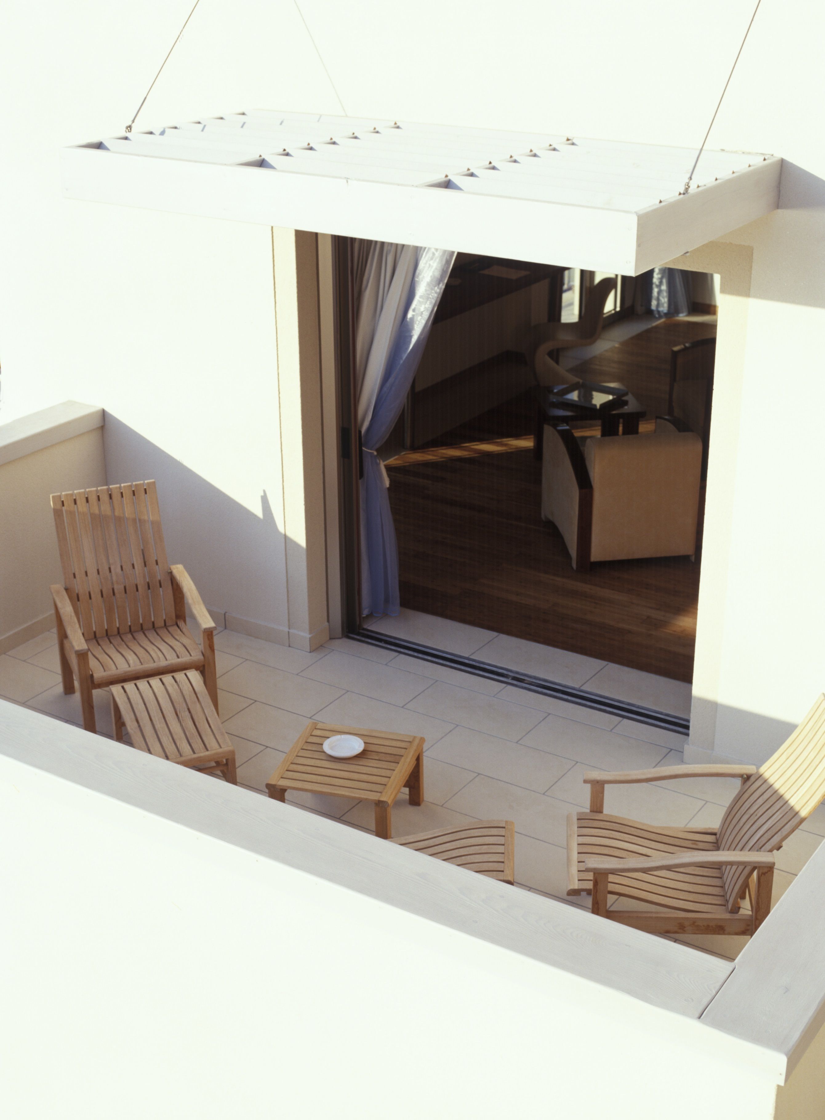 A balcony with wooden furniture, including chairs and a table.