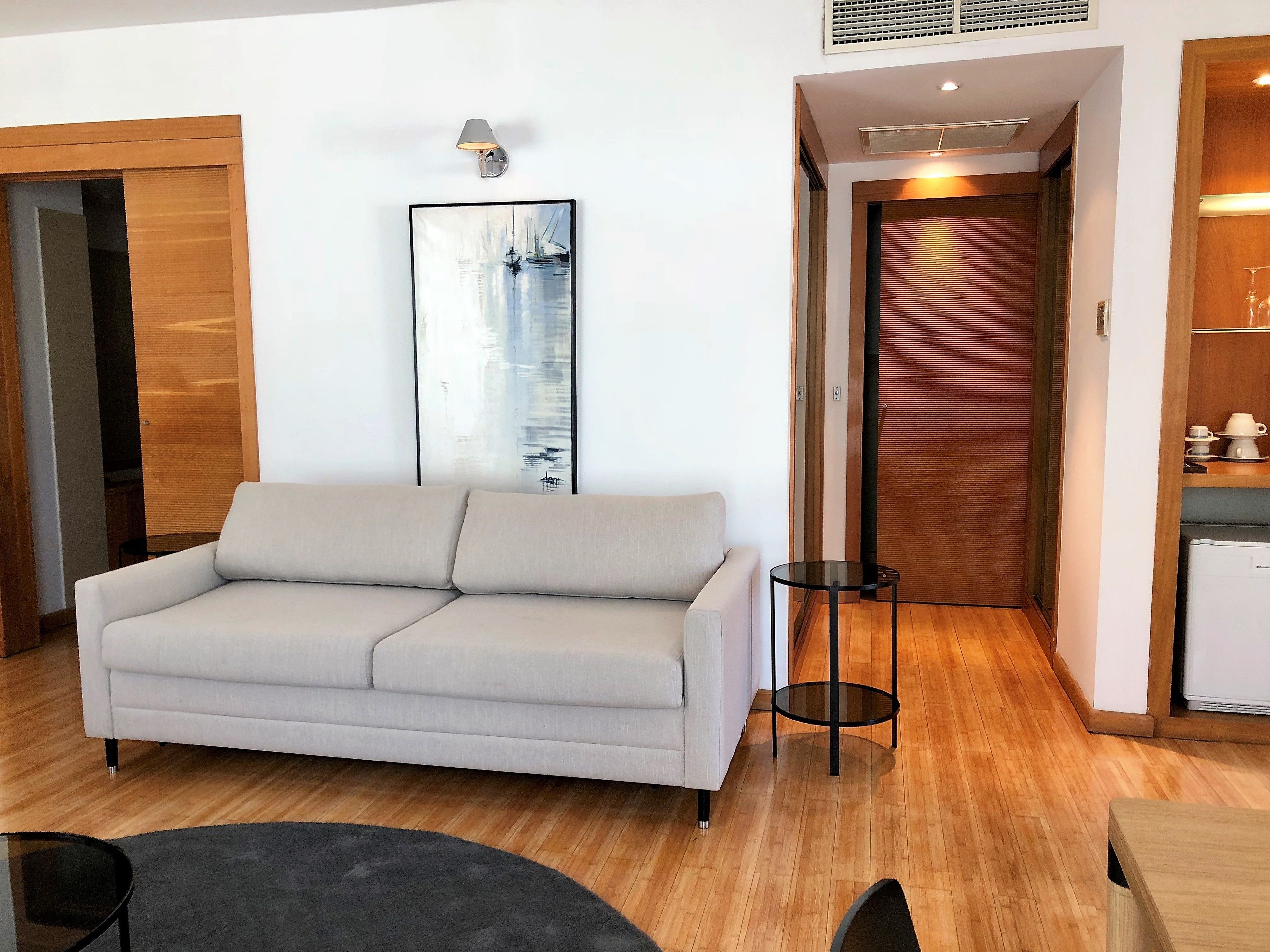 A modern living room with a sofa, a small table, and a painting on the wall.