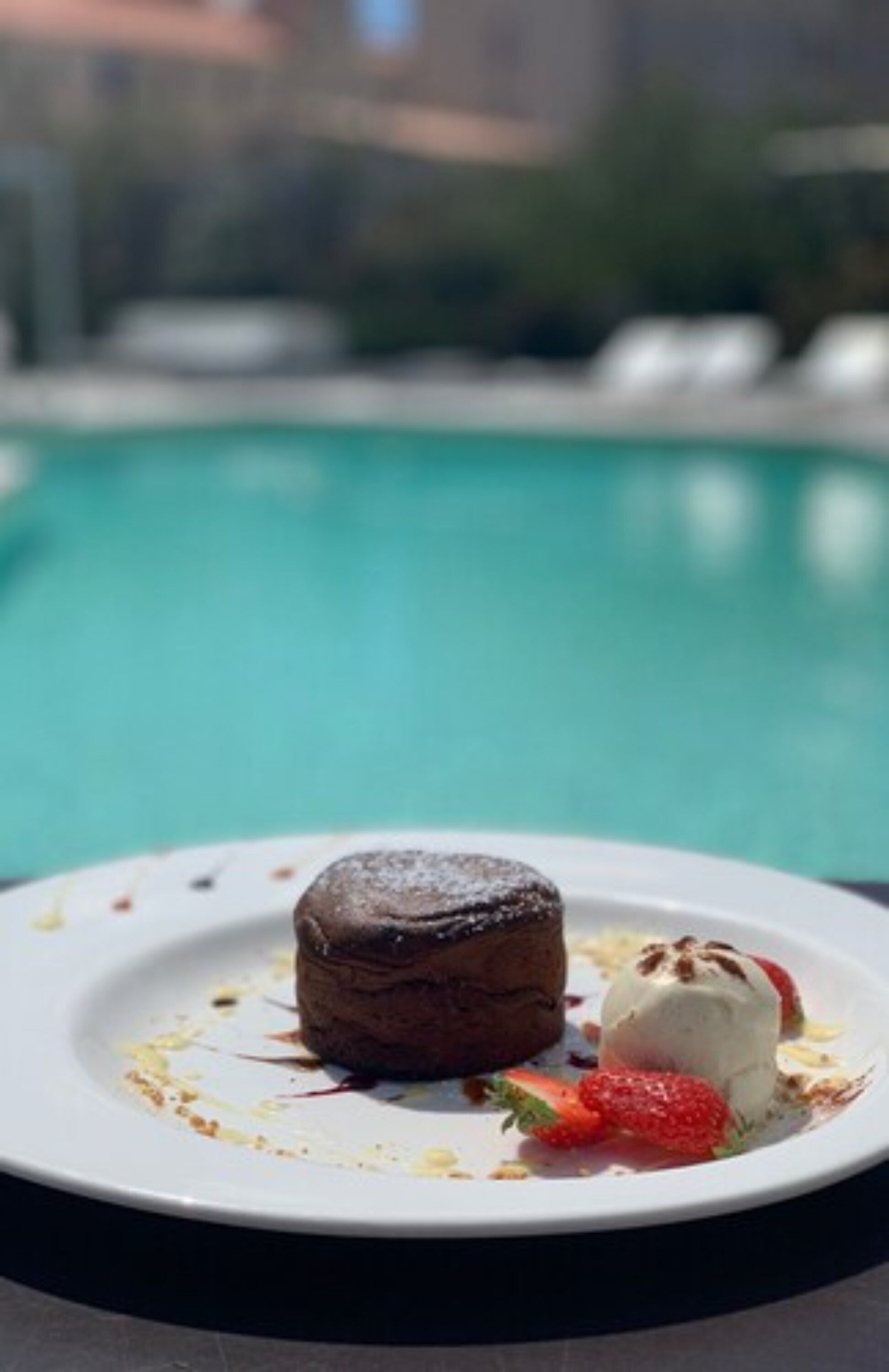 A dessert on a plate by a poolside.