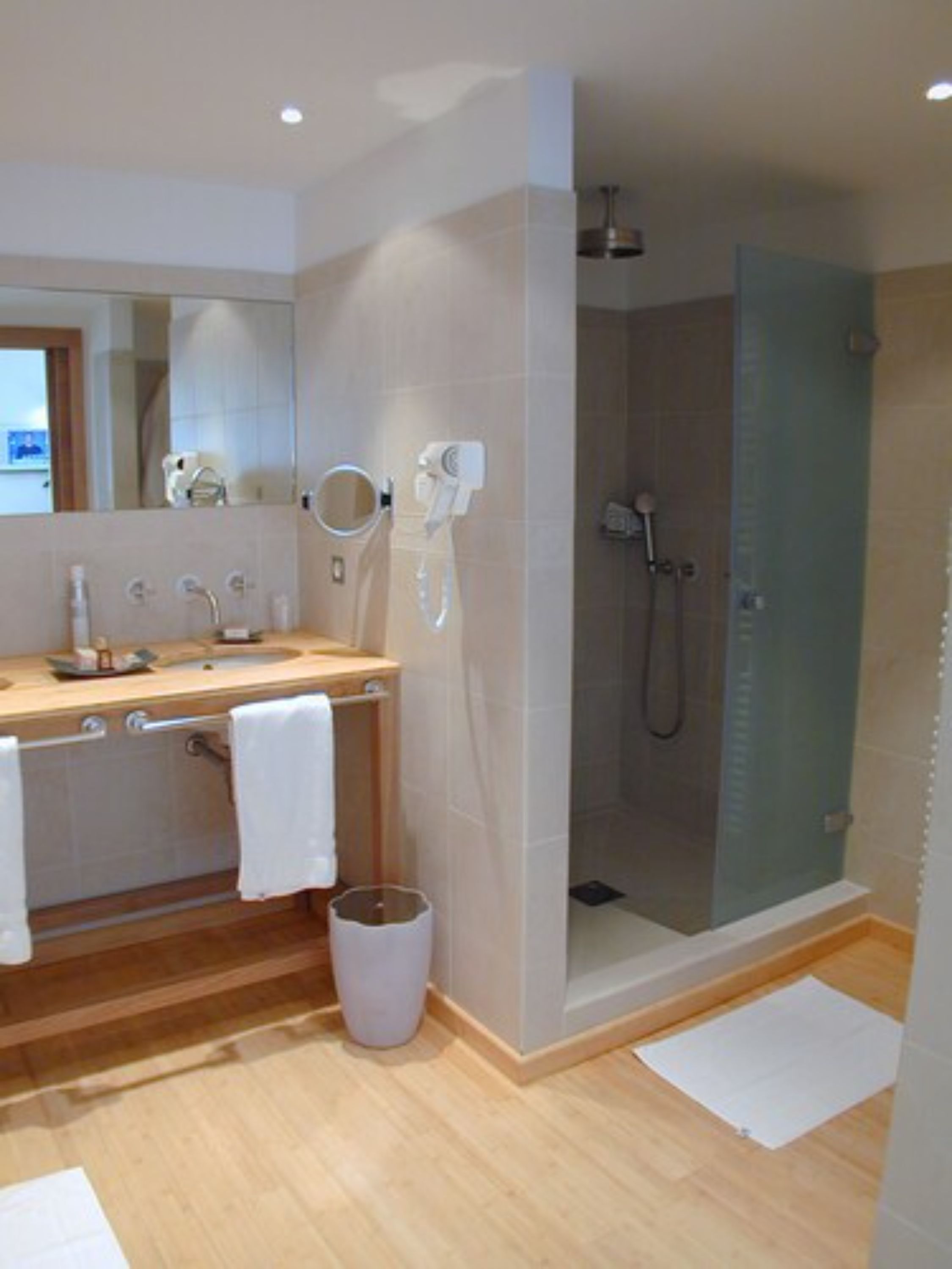 A modern bathroom with a wooden vanity, a glass shower enclosure, and a mirror above the sink.