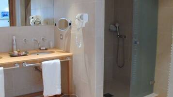 A modern bathroom with a wooden vanity, a glass shower enclosure, and a mirror above the sink.