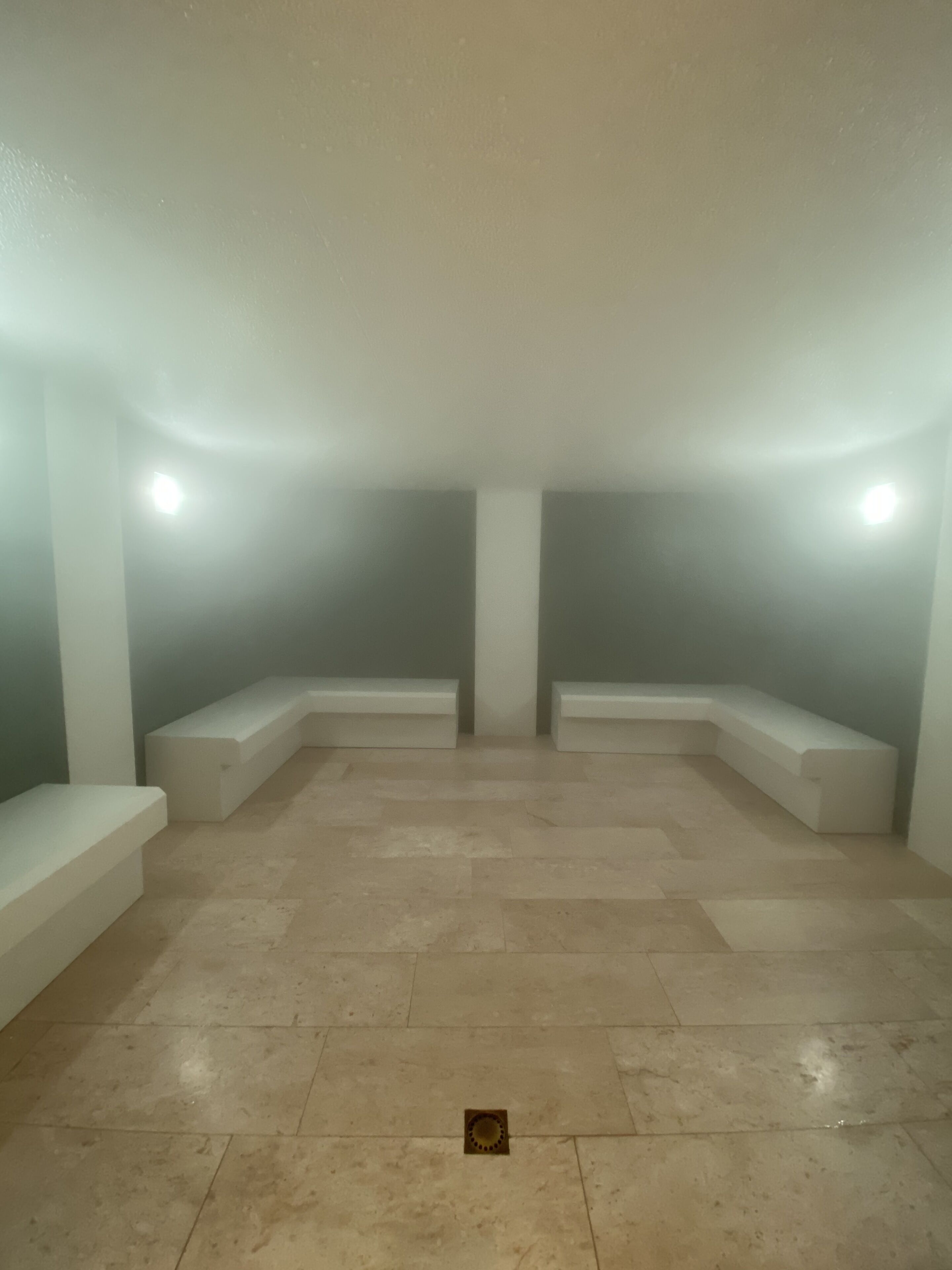 Una habitación con techo alto, iluminación empotrada y suelo de baldosas.
