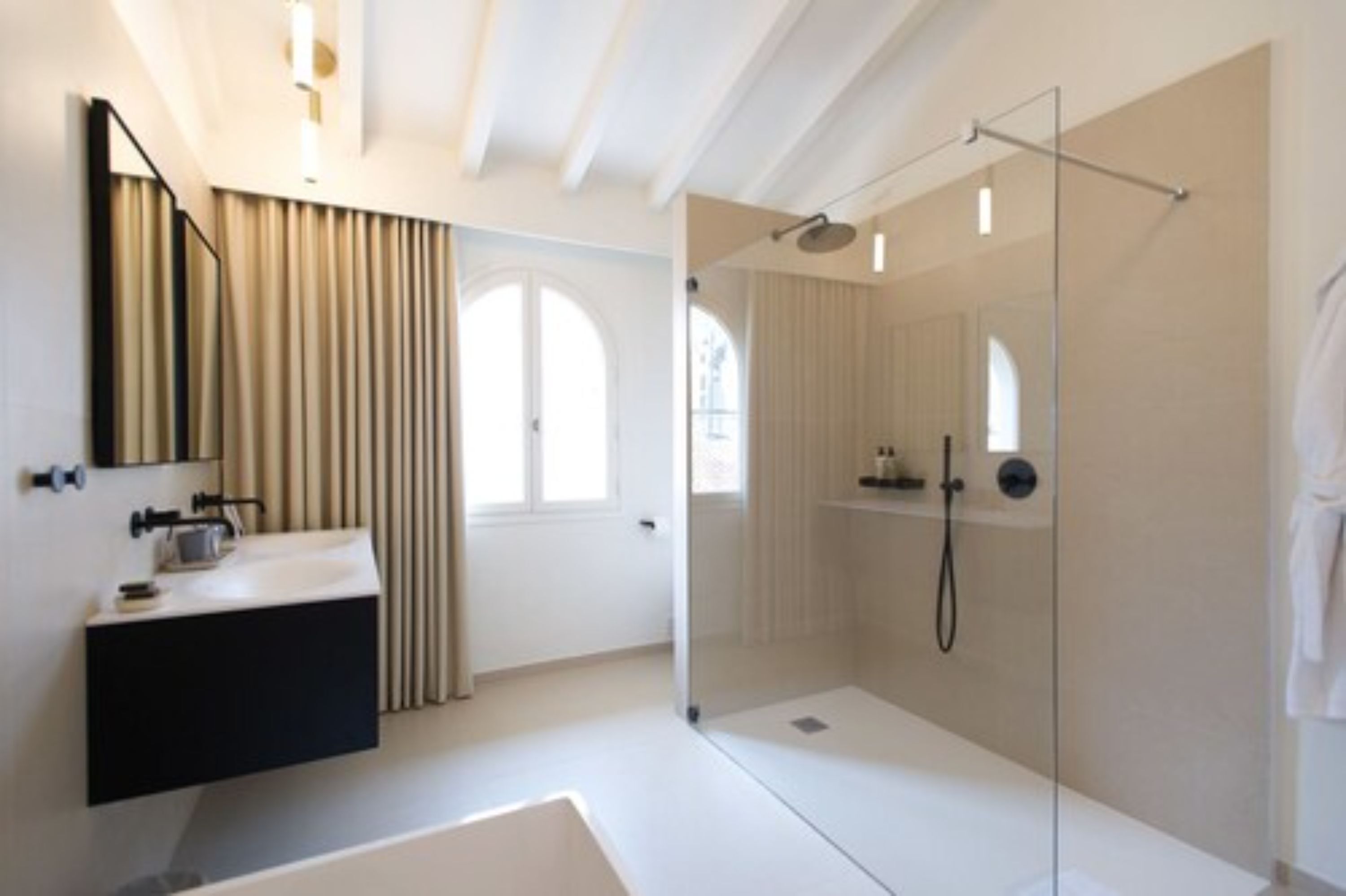 A modern bathroom with a glass-enclosed shower, a white sink, and a large mirror.