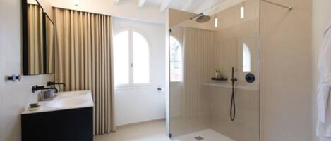 A modern bathroom with a glass-enclosed shower, a white sink, and a large mirror.