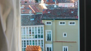 Vista de un paisaje urbano a través de una ventana, con una mezcla de edificios tradicionales y modernos con tejados rojos.
