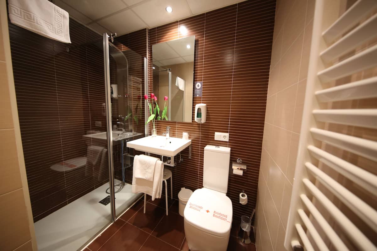A modern bathroom with a glass shower enclosure, a white sink, and a toilet.