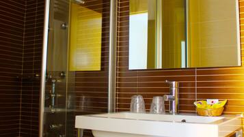 A bathroom with a glass shower enclosure, a white sink with a mirror above it, and two white towels hanging on a rack.