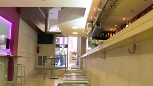 Un interior moderno con una zona de bar, una escalera y una entrada visible a otra sección.