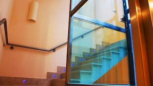 Una escalera moderna con barandales de vidrio y pasamanos, que conduce a un piso superior.