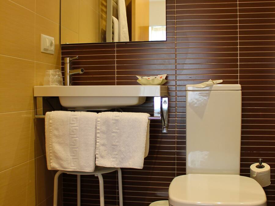 A bathroom with a white toilet, a sink with a mirror above it, and a towel rack with two white towels.