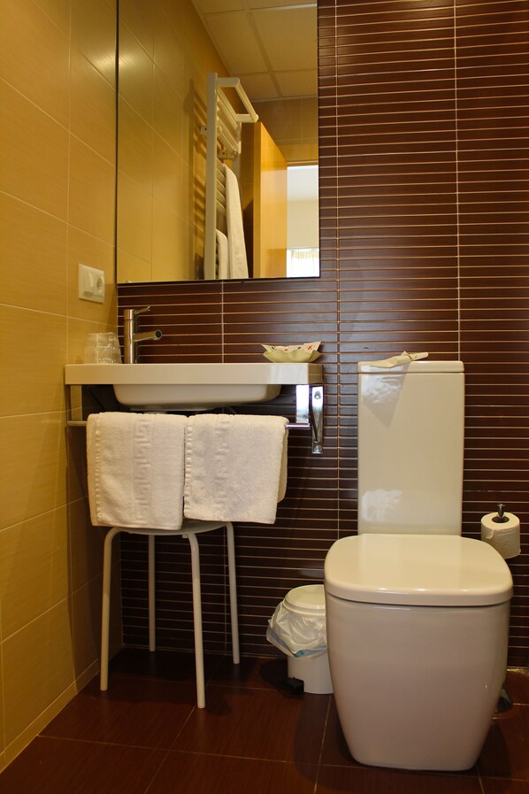 A bathroom with a white toilet, a sink with a mirror above it, and a towel rack with two white towels.