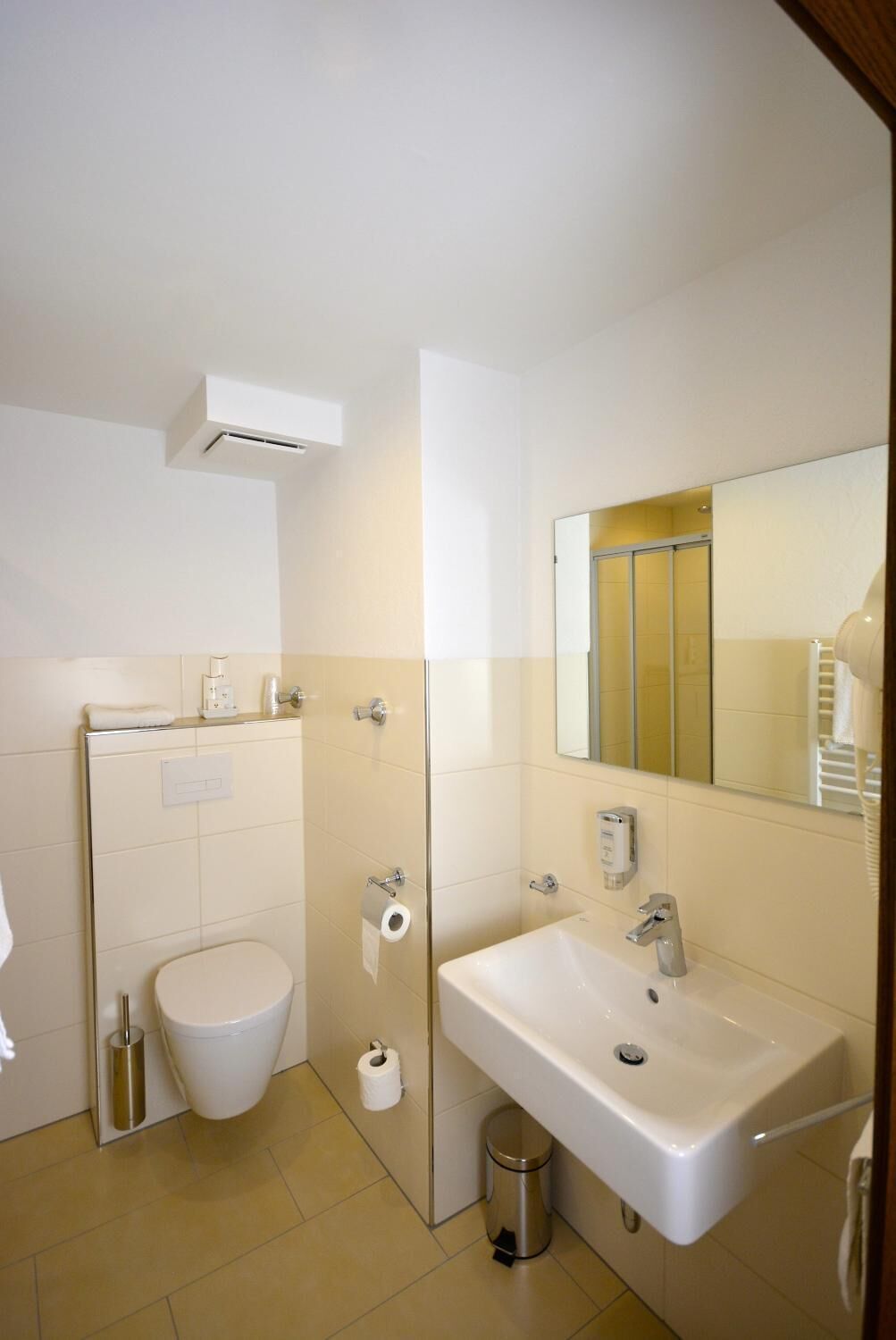 A modern bathroom with a toilet, sink, and mirror.