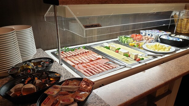 A buffet with various food items including meats, cheeses, and condiments.