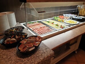 Un buffet proposant une variété de plats, notamment des viandes, des fromages et des accompagnements.