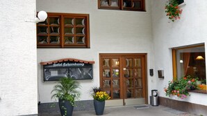A hotel entrance with a tiled roof, a sign reading "Hotel Lehrenkamp", and potted plants.