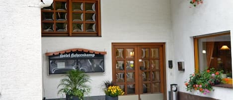 A hotel entrance with a tiled roof, a sign reading "Hotel Lehrenkamp", and potted plants.