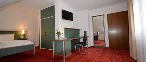 Una habitación de hotel con cama, escritorio, silla y espejo.