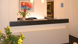 A reception area with a counter, pendant lights, a painting, and a potted plant.
