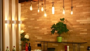 A modern kitchen with wooden wall panels, hanging light bulbs, a green potted plant, and various kitchen items on the counter. - Hotel Casa Arcas (Villanova)