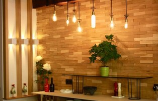Una cocina moderna con paneles de madera, lámparas colgantes, una planta en maceta verde y varios utensilios de cocina sobre la encimera.