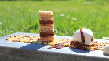 A dessert with a layered cake and a scoop of ice cream on a stone surface.