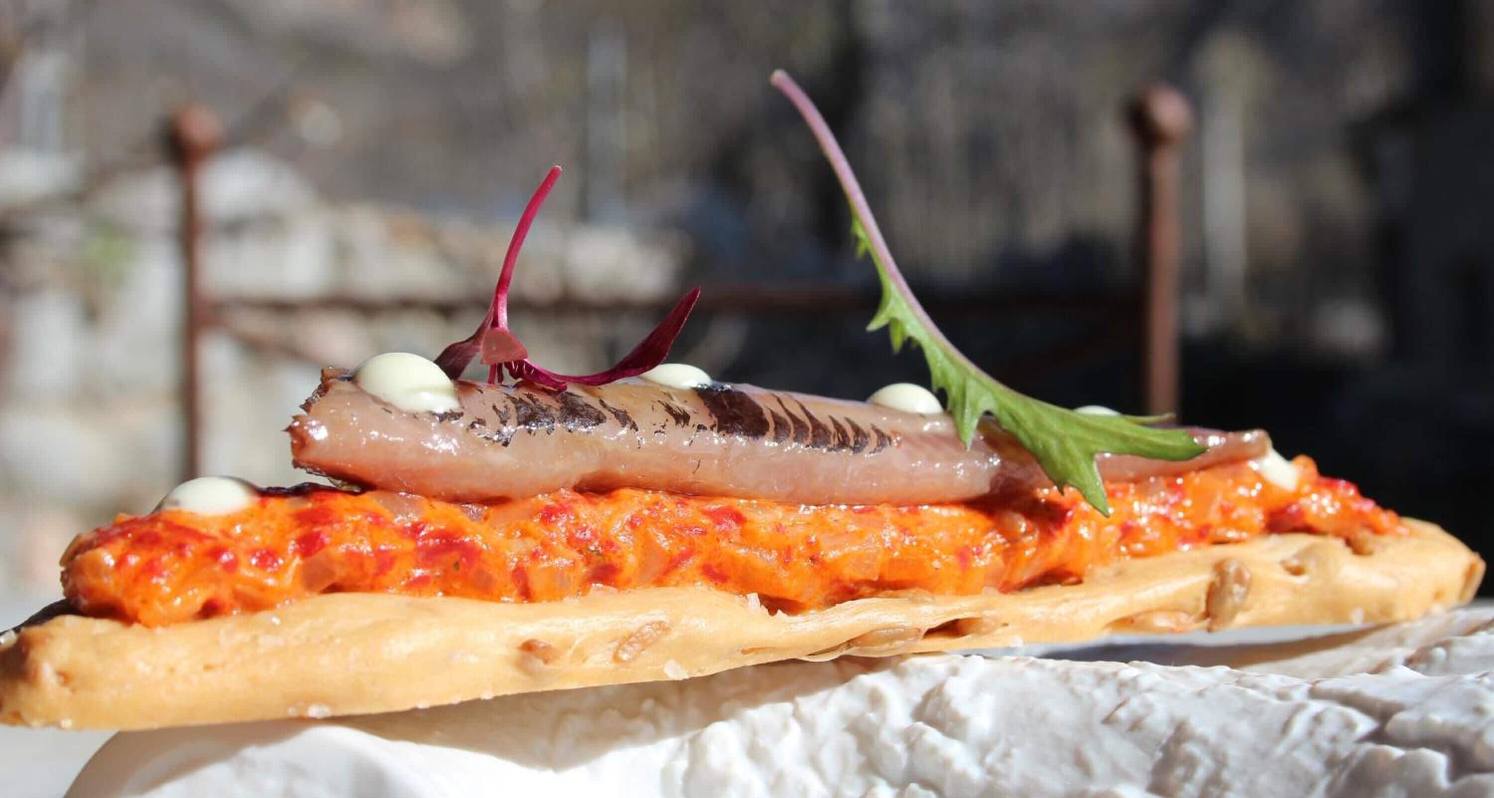 A pizza with toppings and a side of white sauce.