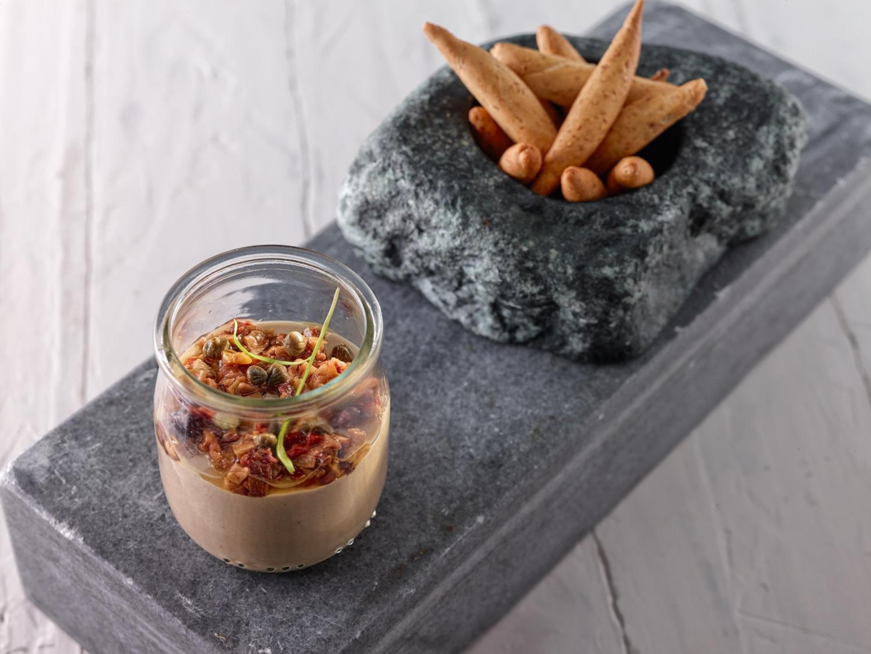 Un tarro de comida con un mortero y pilón de piedra, y un plato de galletas.