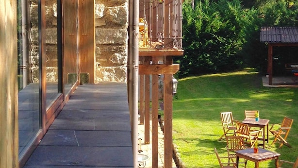 A stone building with a wooden balcony and outdoor seating area. - Hotel Casa Arcas (Villanova)