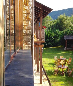 A stone building with a wooden balcony and outdoor seating area. - Hotel Casa Arcas (Villanova)