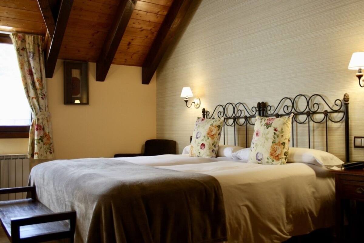Quarto com uma cama grande, duas mesas de cabeceira, um criado-mudo, uma cadeira e uma janela com cortinas.