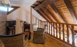 A cozy room with a wooden ceiling, a television, a small table with a kettle, and wicker chairs. - Hotel Casa Arcas (Villanova)