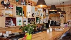 A bar area with wooden shelves, bottles, glasses, and a plant. - Hotel Casa Arcas (Villanova)