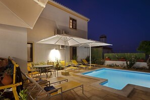 A poolside area with lounge chairs and a table, surrounded by a building with a tiled roof and a swimming pool. - Bética Hotel Rural (Serpa)