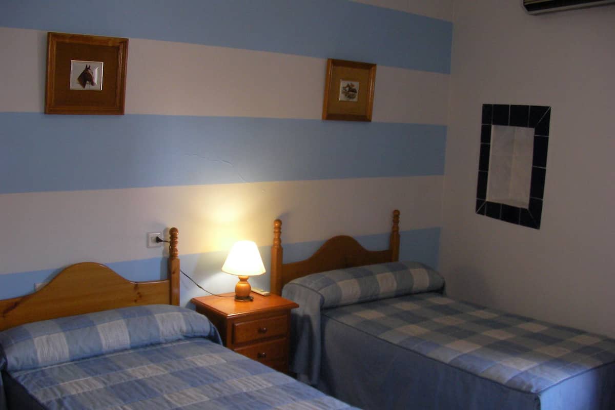 Una habitación con dos camas, una mesita de noche y un espejo instalado en la pared.