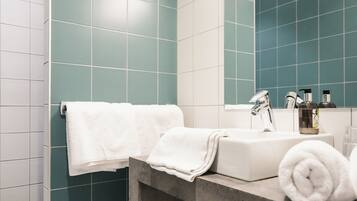 A bathroom with teal tiles, a white sink, a mirror, and a towel rack.